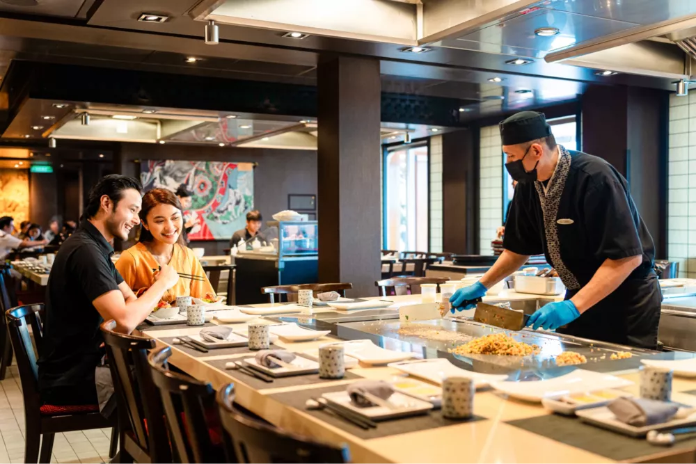 Couple seated at a teppanyaki grill watching the chef cook